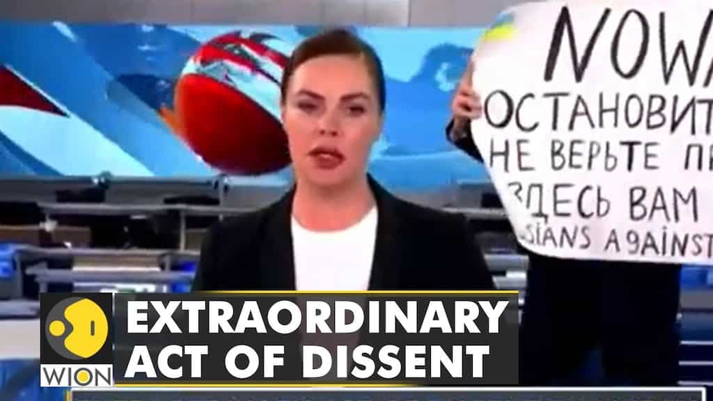 An anti-war protester disrupts live bulletin, sign says 'Stop the war they are lying'