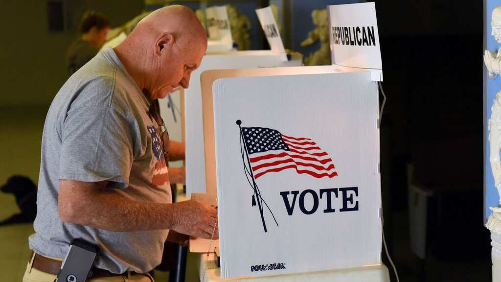 People cast their ballots in secured boxes as early voting for US midterm election begins
