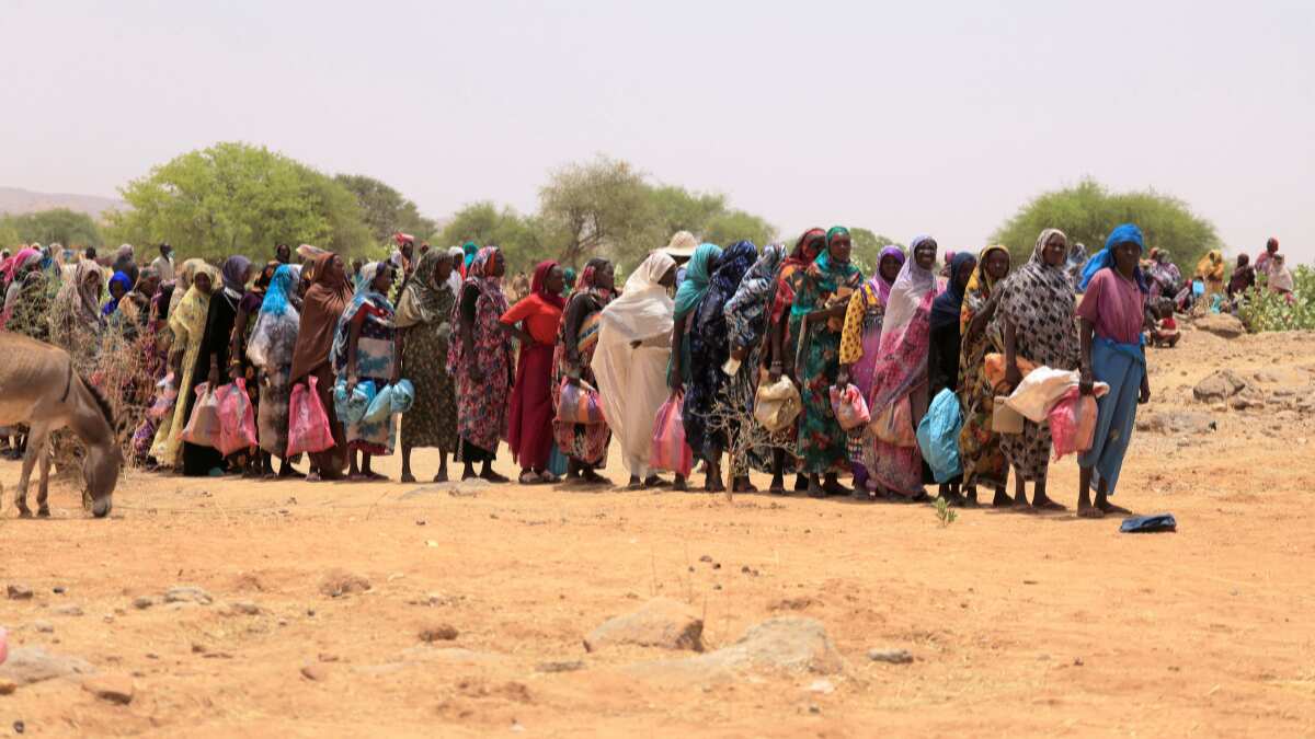 Sudanese refugees await their turn to be placed in a refugee camp