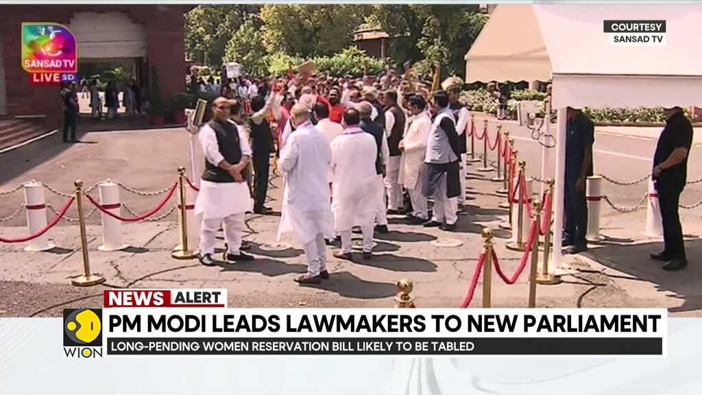 Indian lawmakers walk to the new Parliament Building carrying a copy of the Constitution