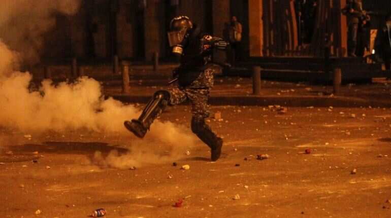 A riot police kicks a tear gas canister during a protest against a ruling elite