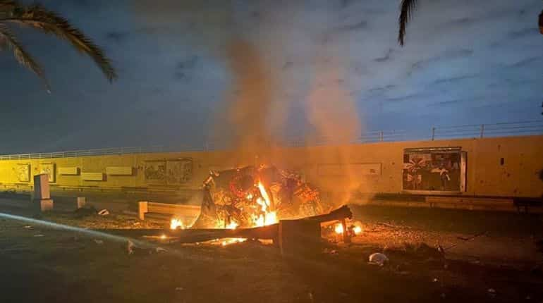 Burning debris are seen on a road near Baghdad International Airport