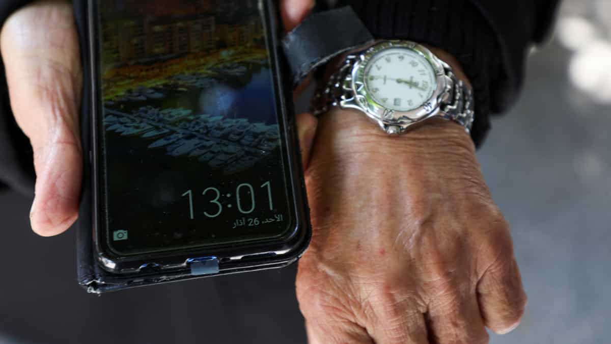 A Lebanese Muslim shows the different timings on his watch and mobile phone