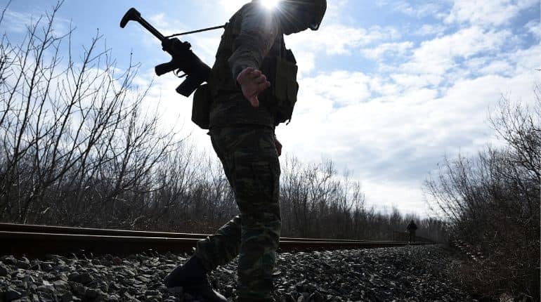 Greek soldiers walk on the railway tracks as they patrol next the Greek-Turkish border near the village of Marasia, in the region of Evros, Greece