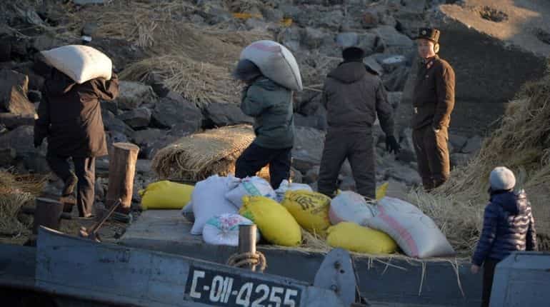A North Korea soldier stands guard as people unload a boat on the Yalu River which separates the North Korean town of Sinuiju from the Chinese border town of Dandong on the second anniversary of the death of former leader Kim Jong-Il, December 17, 2013