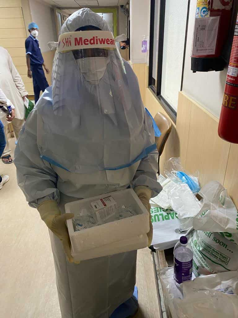 Me in a PPE kit with the Tocilizumab vial.