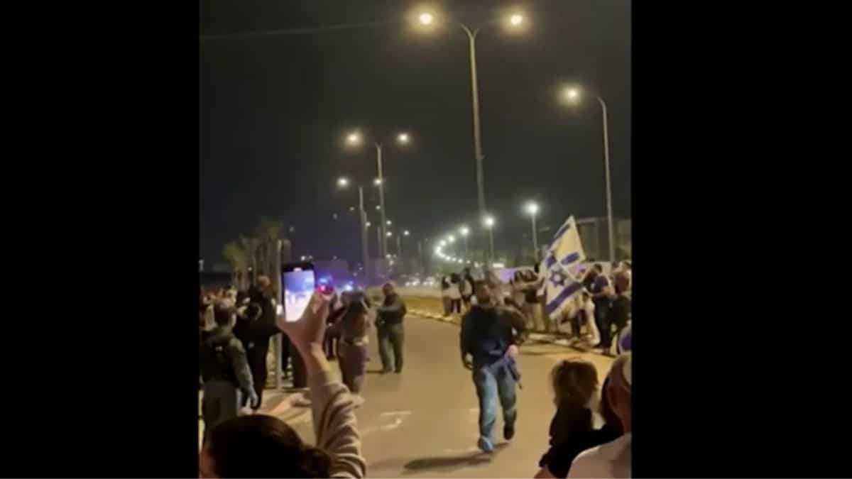 Car conoy carrying hostages passing by En Route to nilitary base, Israelis gathered near military base cheering