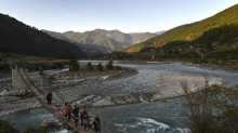 This photo taken on December 6, 2019 shows tourists walking on a suspension bridge over the Puna Tsang Chhu river in Punakha province in Bhutan