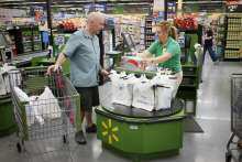 A customer speaks to the cashier as he checks out at a Walmart Neighborhood Market in Bentonville, Arkansas, June 2014