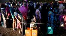 People stand in a queue to buy kerosene oil for home use at a petrol station in Colombo.